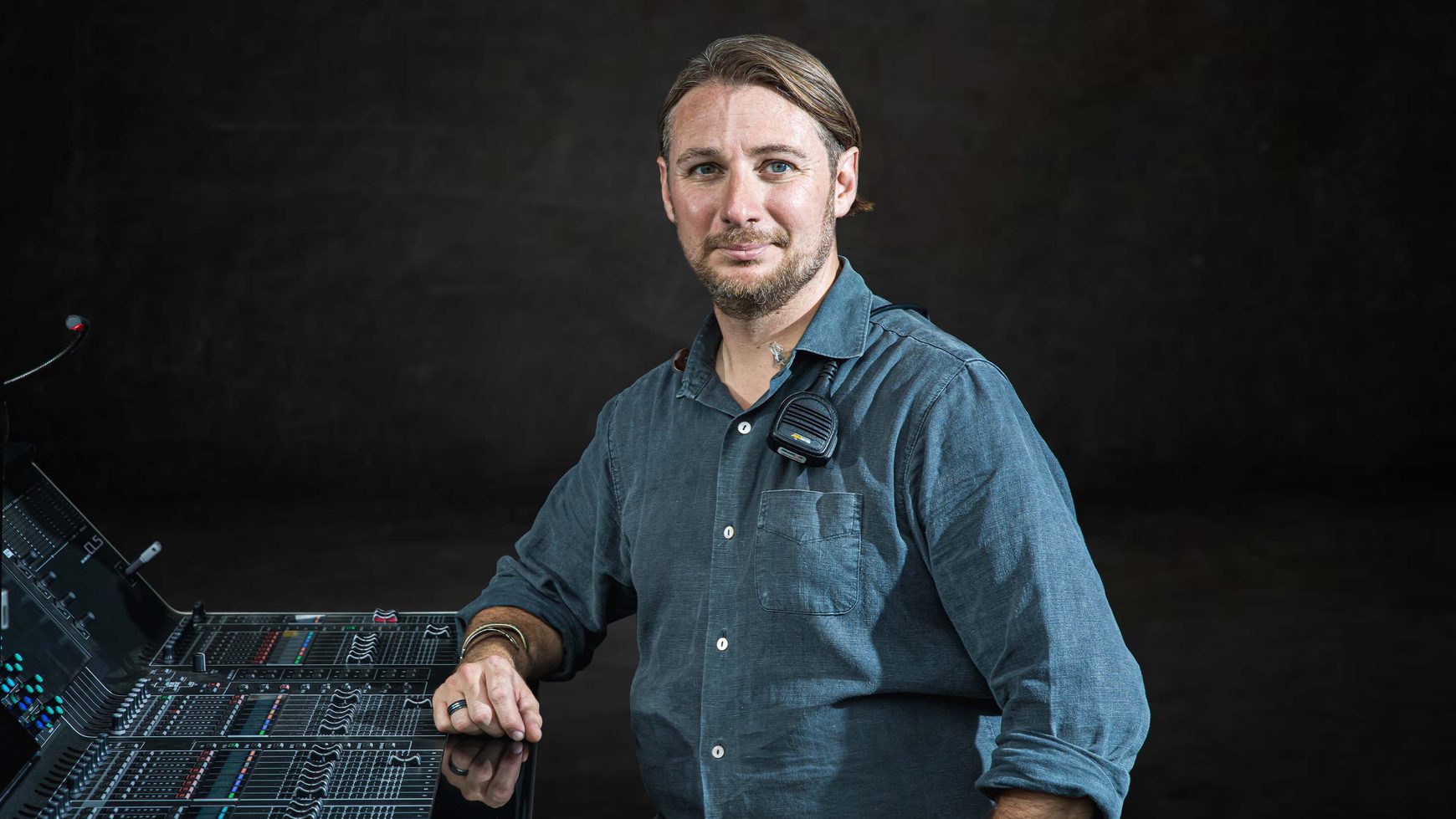 Sage Anthony at a front of house console with a radio clipped to his shirt