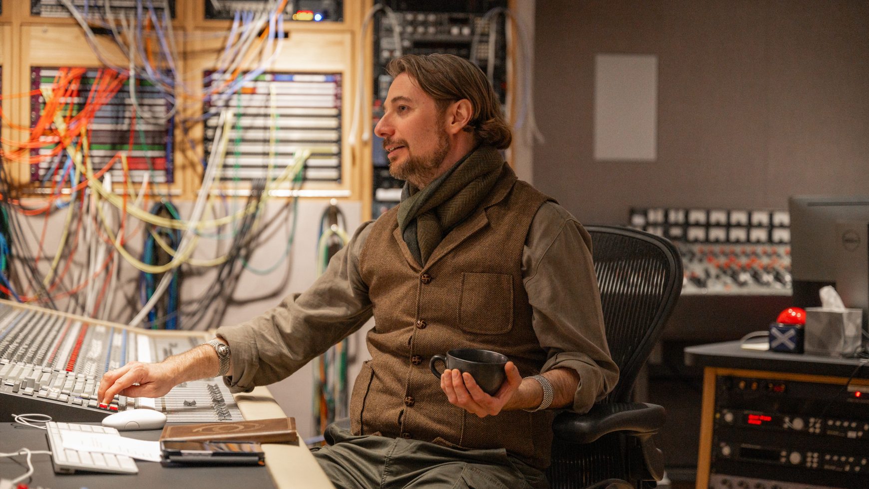 Sage Anthony at the console in a studio control room, patch bay behind him